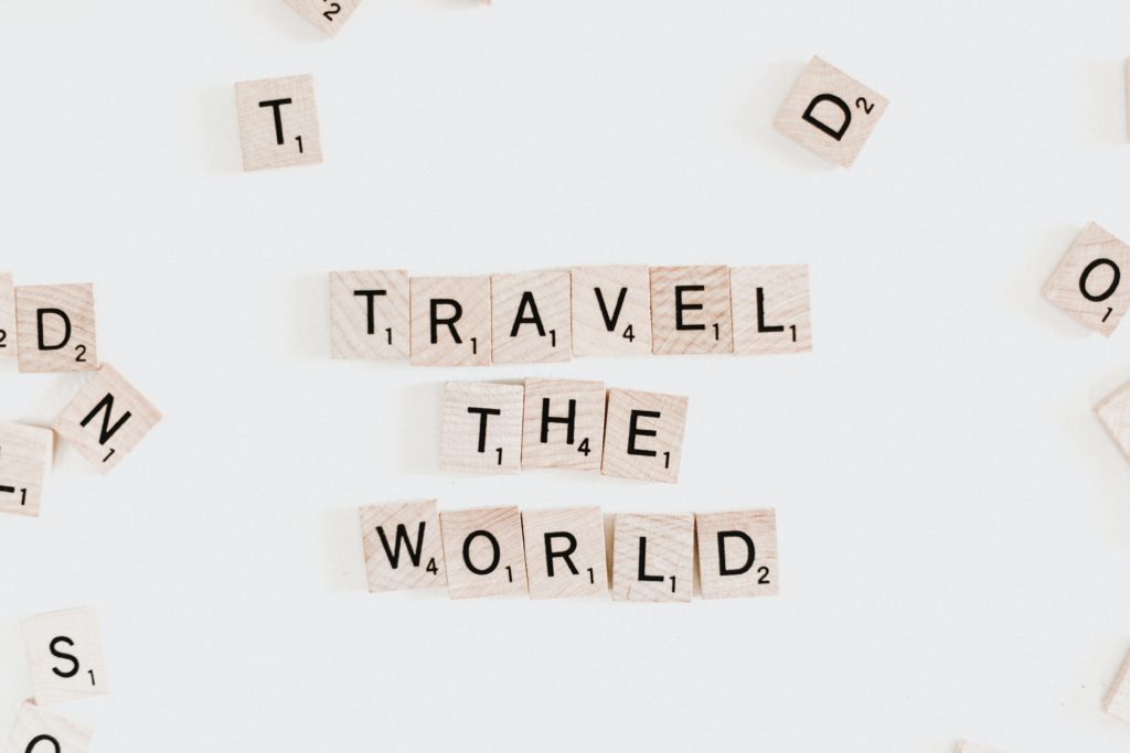 scrabble pieces spelling out 'travel the world'