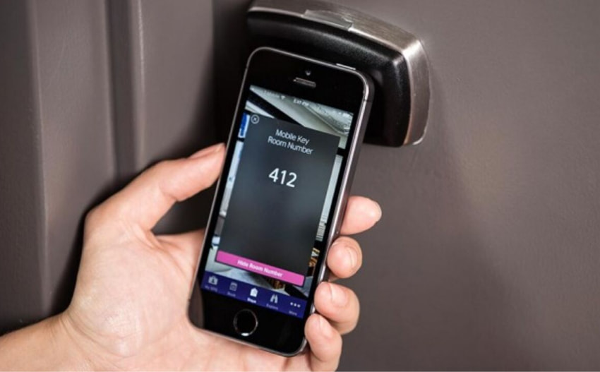 a hand holding a mobile device with a digital key for unlocking the hotel door